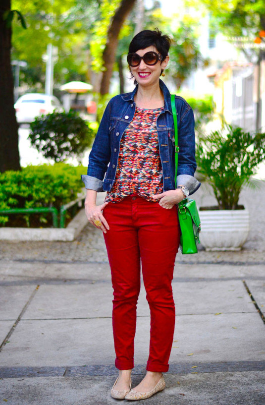 calça vermelho fechado, blusa manga comprida estampa quadriculada em vermelho, verde, azul e bege, jaqueta jeans escura, sapatilha nude, bolsa verde