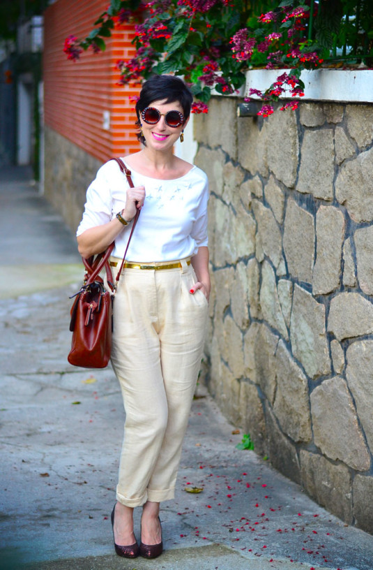 blusa branca com estrelas brancas aplicadas, calça bege claro de linho e cintura alta, cinto dourado, scarpin de gliter vinho e bolsa marrom