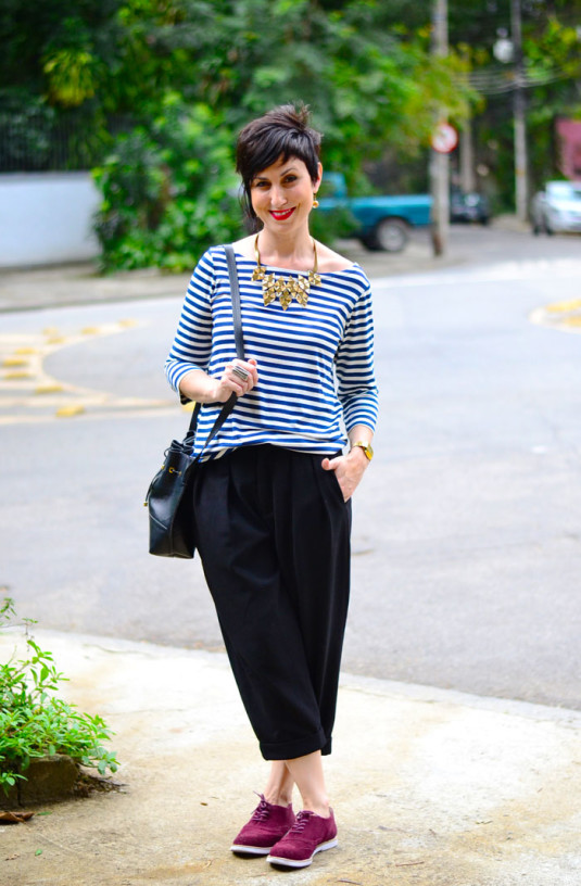 blusa estilo náutico com listras brancas e azuis, calça preta de alfaiataria curta, oxford berinjela, colar dourado de triângulos e bolsa saco preta