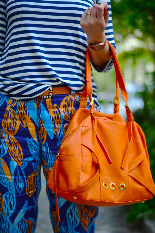 calça estampa azul e laranja de linho, blusa de manga três quartos de listras azuis, sapatilha cinza e bolsa laranja