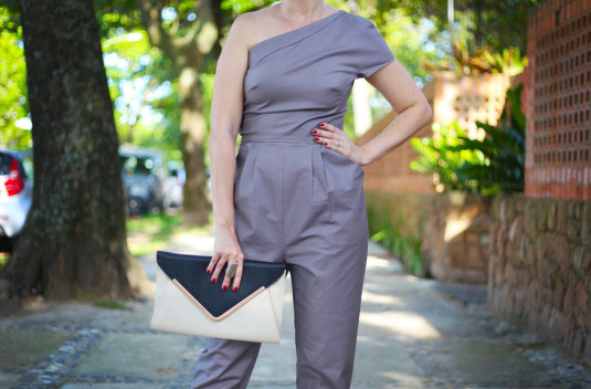 macacão de um ombro só cinza alfaiataria, carteira creme e preta, scarpin dourado, brincos prata