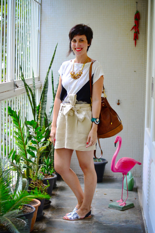 camiseta branca com triangulos pretos, saia de linho cru, sandália rasteira com estampa de folhagens pb, bolsa saco marrom tressê